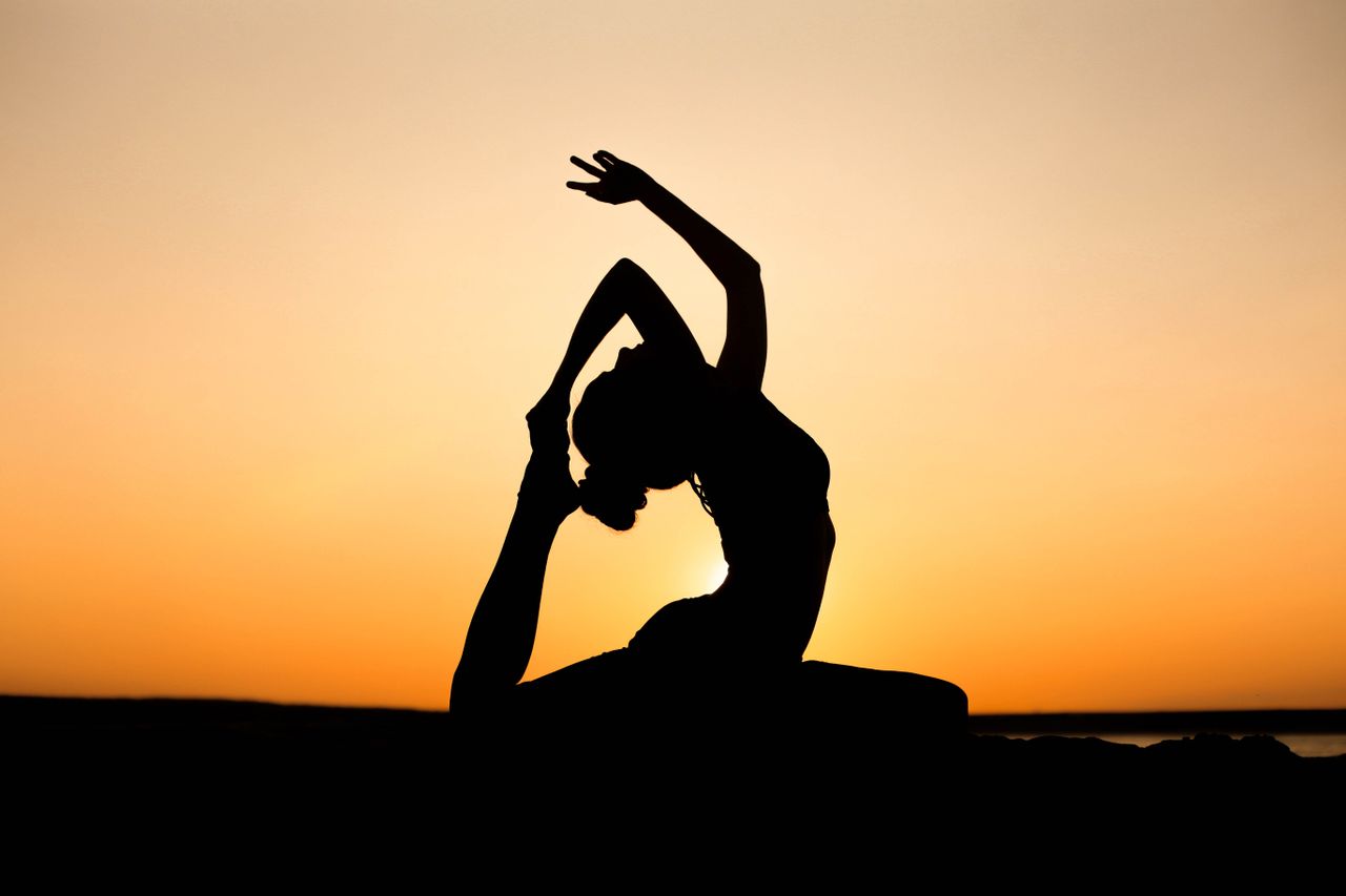 The Art of Drawing Readers In: Your attractive post title goes here A woman in a yoga pose silhouetted against a vibrant sunset sky, embodying peace and wellness.